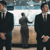 two bodyguards waiting for businessman standing at reception counter