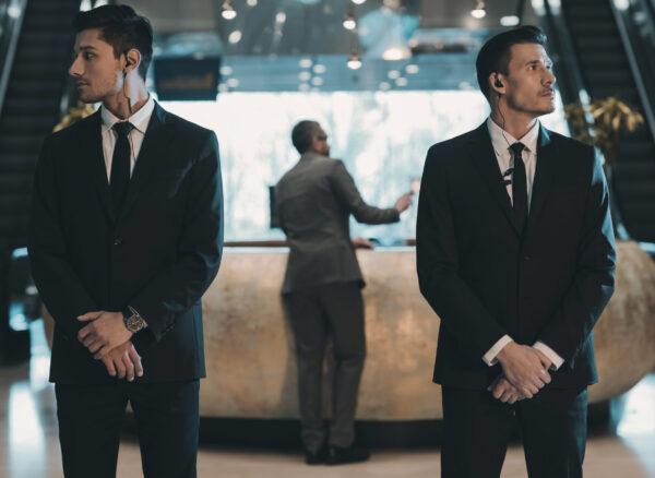 two bodyguards waiting for businessman standing at reception counter
