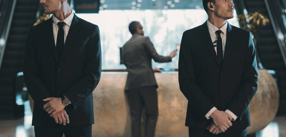 two bodyguards waiting for businessman standing at reception counter